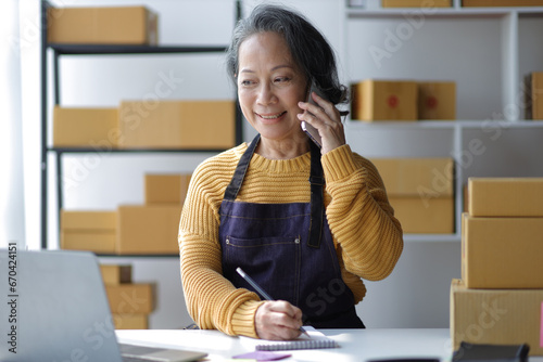 Senior female entrepreneur, small business owner, online seller working with parcel boxes preparing to ship orders from the internet, retirement hobby.