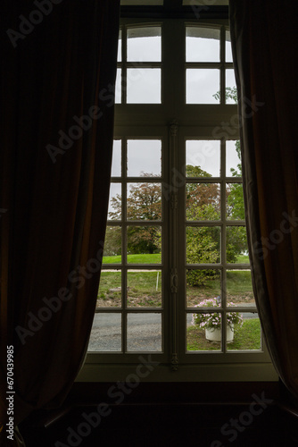 Window with curtains in the French Chateau overlooking the garden area
