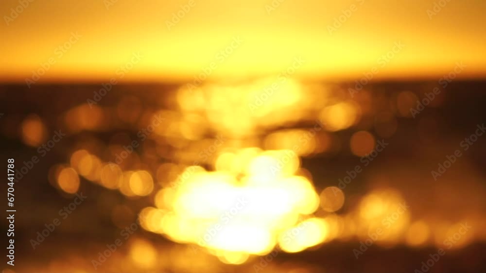 Blurred golden sea at sunset. The sun reflects and sparkles on the waves with bokeh, illuminating the golden sea. Holiday recreation concept. Abstract nautical summer ocean sunset nature background. Blurred golden sea at sunset. The sun reflects and sparkles on the waves with bokeh, illuminating the golden sea. Holiday recreation concept. Abstract nautical summer ocean sunset nature background.