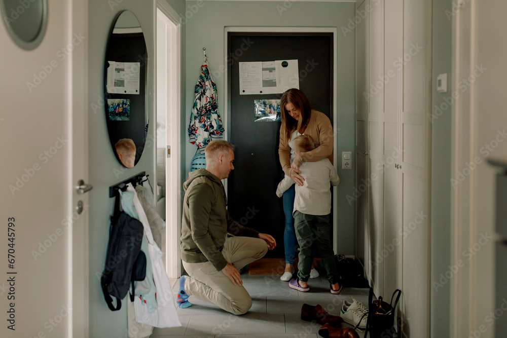 Boy embracing mother by father kneeling in mudroom at home Boy embracing mother by father kneeling in mudroom at home
