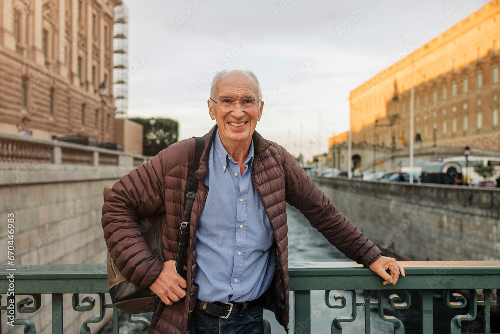 Portrait of happy senior man leaning on railing over canal Portrait of happy senior man leaning on railing over canal