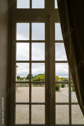 Window with curtains in the French Chateau overlooking the garden area