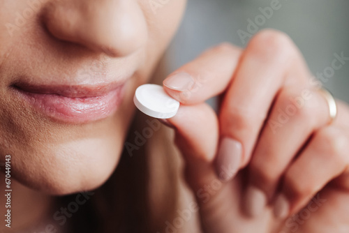 White pill in fingers. Woman holding drug. Narcotics background. Young girl taking drugs. Hand holding white tablet. Illness cure. Medication dose. Painkiller problem. Closed mouth smile and tablet. photo