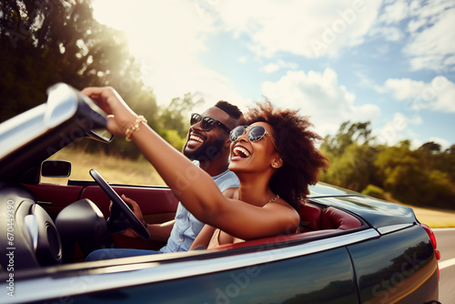 Happy smiling young couple driving vintage cabriolet car, going on the fun road trip together photo