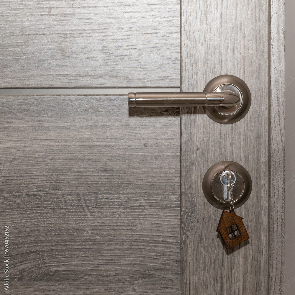 Buy Or Rent concept. Keys with trinket in shape of house in the door keyhole. Buy Or Rent concept. Keys with trinket in shape of house in the door keyhole.