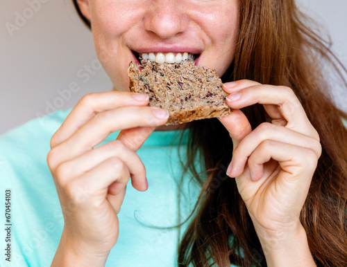 Tableau sur toile Young female person eating healthy food, biting multigrain bread close-up
