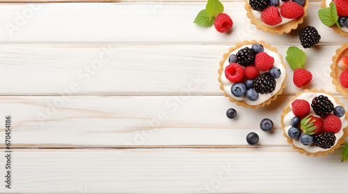 Tartlets with different fresh blue berries on light wooden table space for text background 16-9