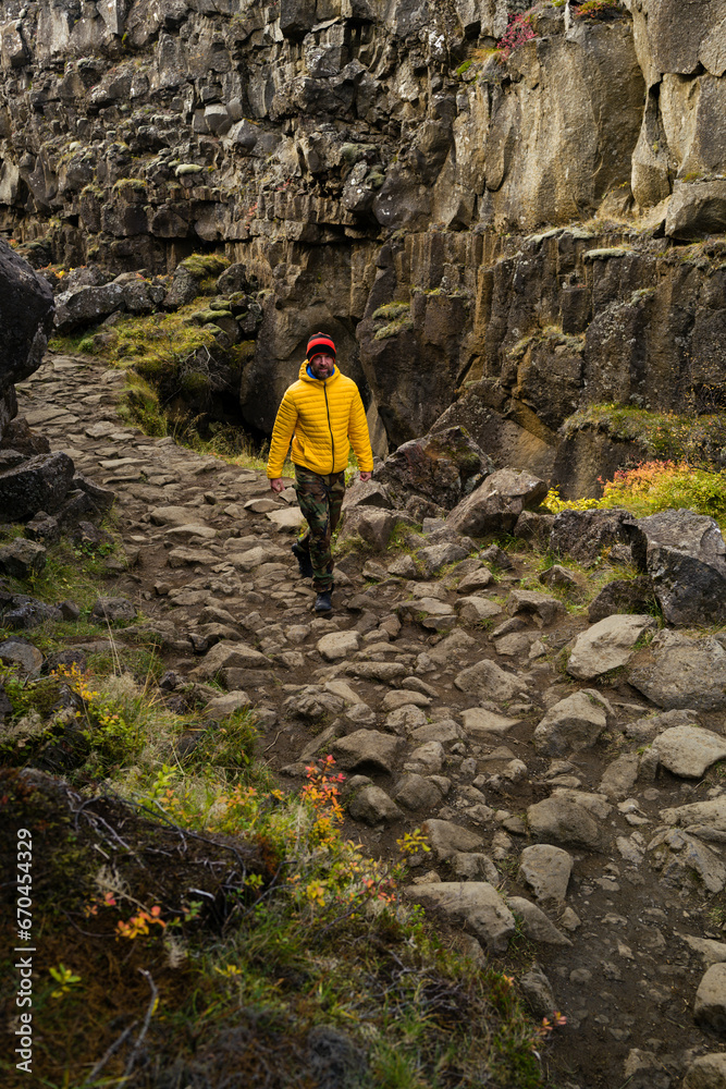 Man wearing a yellow jacket walking between the tectonic plates in the Thingvellir national park