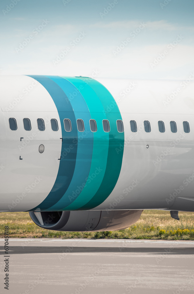 Vertical image of fuselage section with blue-teal colored rings. Close-up view of airplane parked on apron - fuselage of passenger aircraft. Vertical image of fuselage section with blue-teal colored rings. Close-up view of airplane parked on apron - fuselage of passenger aircraft.