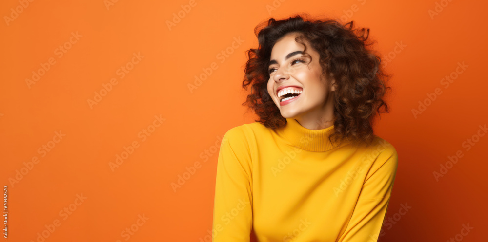 Beautiful happy young smiling brunette woman in yellow sweater on orange or apricot background Beautiful happy young smiling brunette woman in yellow sweater on orange or apricot background