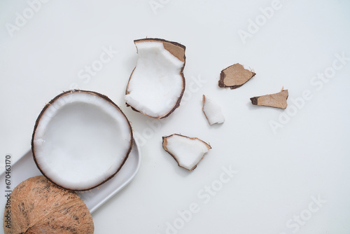 Fresh coconut and white ceramic plate on minimalist background. Scenes for advertising products with natural origins. View from above, flat lay.