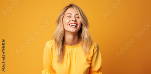 a blonde woman in a yellow dress on an apricot background laughs and rejoices