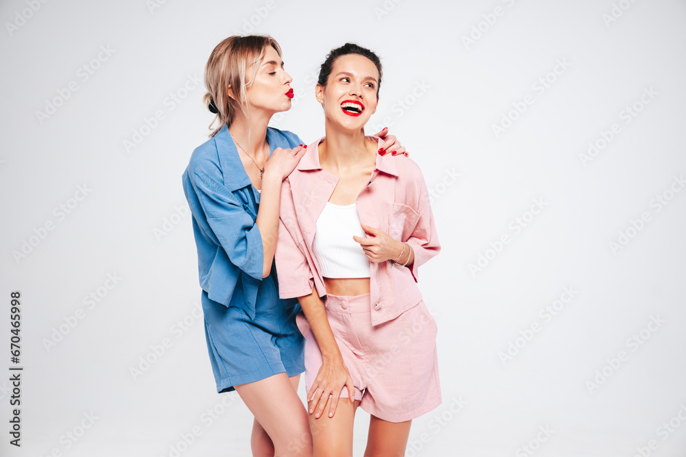 Two young beautiful smiling brunette hipster female in trendy summer clothes. Sexy carefree women posing on white background in studio. Positive models having fun. Cheerful and happy. Isolated Two young beautiful smiling brunette hipster female in trendy summer clothes. Sexy carefree women posing on white background in studio. Positive models having fun. Cheerful and happy. Isolated