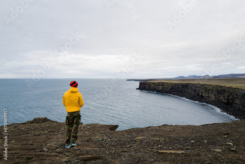 Man in yellow jacket overlooking the cliff in Iceland