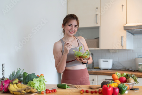 Young woman standing in the kitchen making a salad for health
