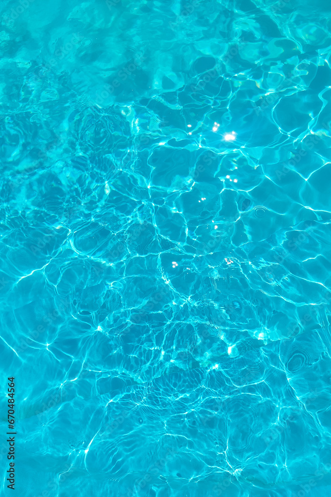 Azure transparent texture of water in a blue pool with splashes from the sun