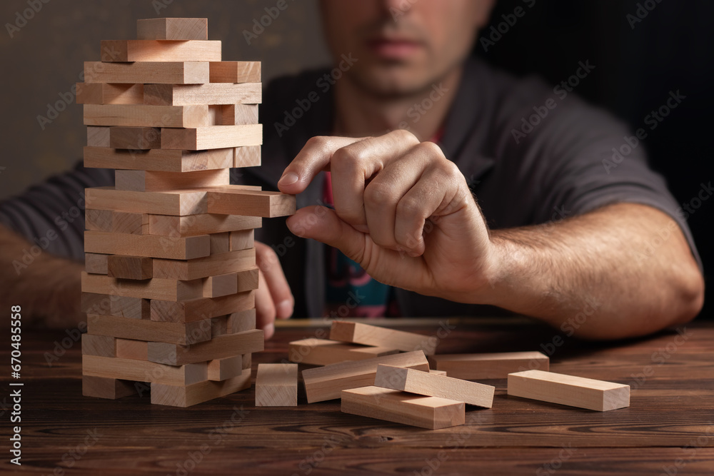 Planning, risk and strategy in business, businessman and engineer gambling placing wooden block on a tower Planning, risk and strategy in business, businessman and engineer gambling placing wooden block on a tower