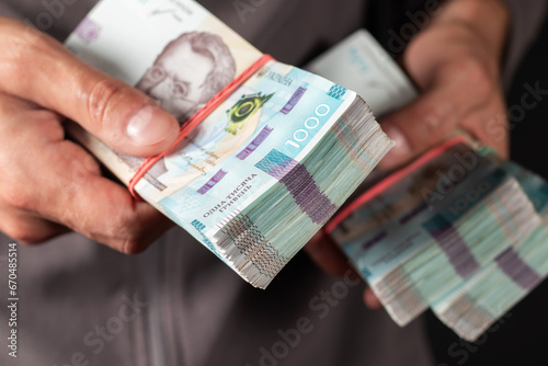 Man holds three bundles of hryvnia in her hand. Ukrainian money. Business concept. 1000 hryvnia banknotes.