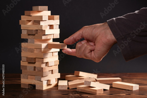 Closeup hand man take one block on The tower from wooden blocks