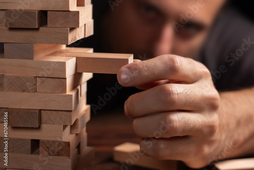 Closeup hand man take one block on The tower from wooden blocks