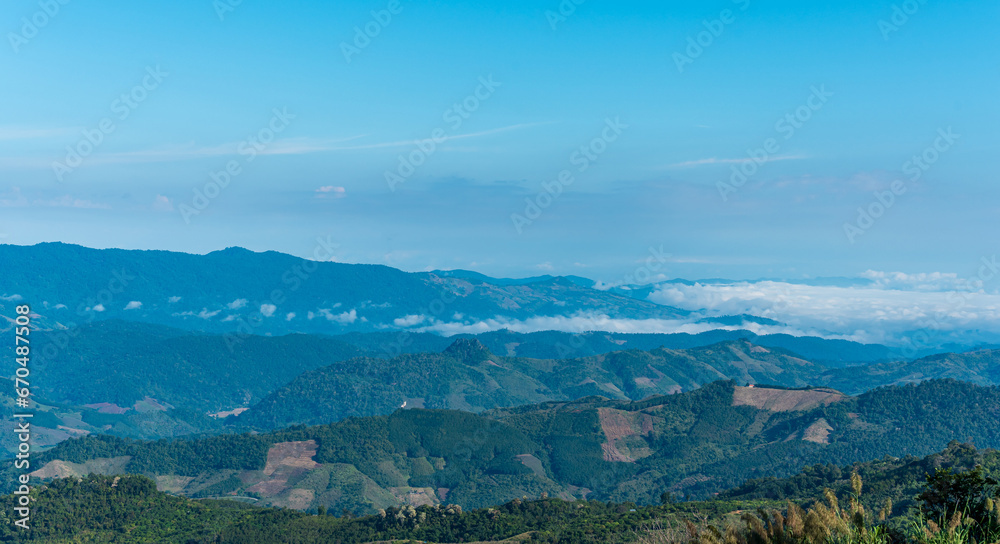 Mountain view in morning with blue sky background. countryside landscape with valley in fog behind the forest on the hill. nature background.