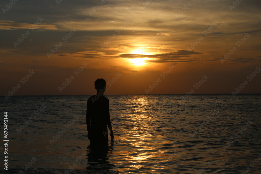 silhouette of a person at sunset, enjoy the sunset while swimming at Karimunjawa beach, Republic of Indonesia