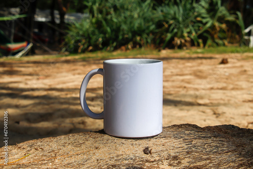 A white mug placed on a log with a view of nature in the background.