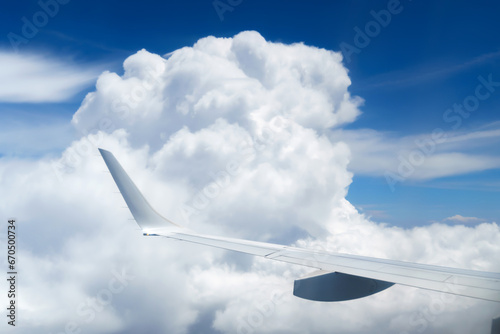 beautiful blue sky with soft clouds and plane wing as abstract background, bird's-eye view from an airplane window, travel concept