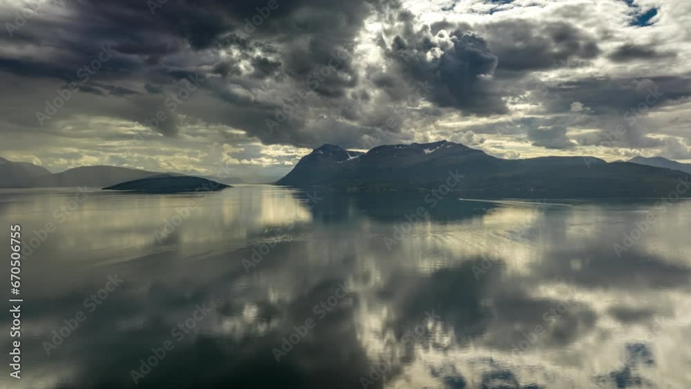 Vassbruna mountain peak and hyper lapse. Water with beautiful reflection of clouds, Norway.