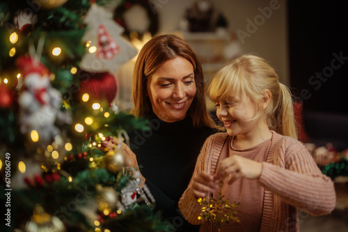Happy mother and daughter decorating a Christmas tree