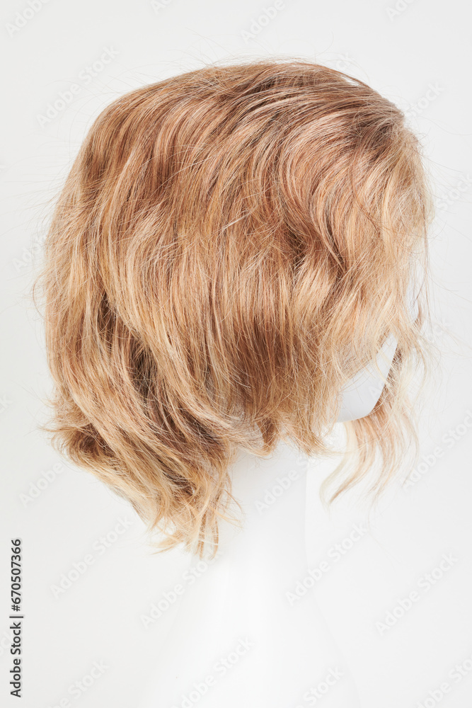 Naklejka premium Natural looking blonde fair wig on white mannequin head. Short hair cut on the plastic wig holder isolated on white background, side view.