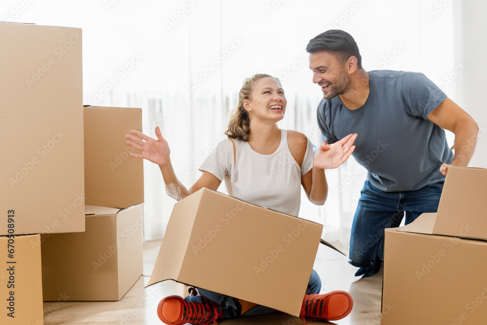 a happy family. a cheerful guy and a girl are sorting out boxes in a new house, a cheerful couple is joking and laughing a happy family. a cheerful guy and a girl are sorting out boxes in a new house, a cheerful couple is joking and laughing