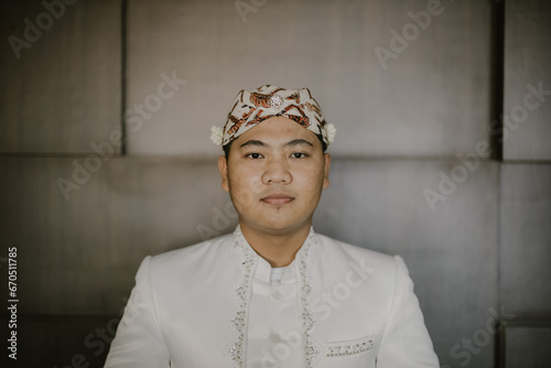 The groom looks handsome and charismatic in traditional Sundanese clothing. 