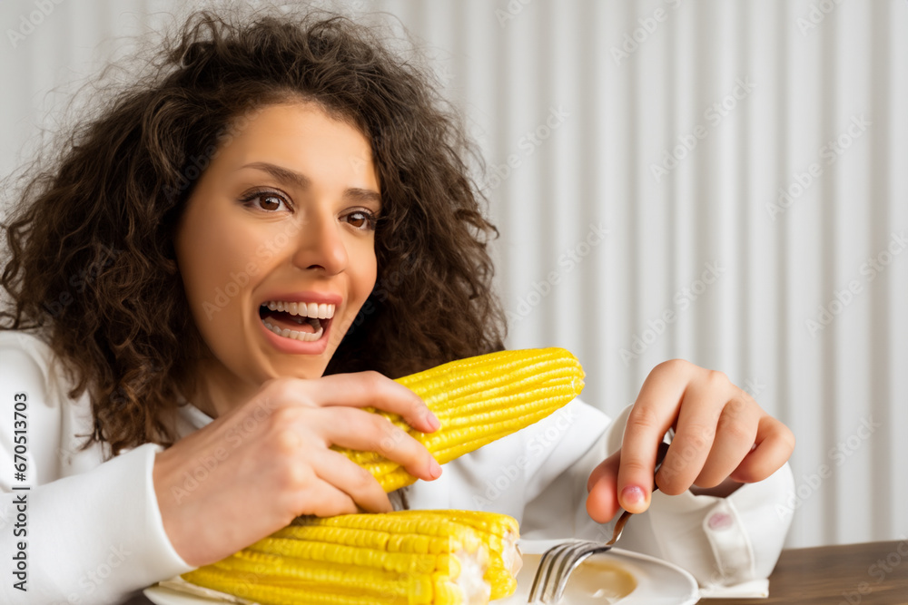 girl eats corn. a young girl sits in the kitchen and eats yellow boiled corn, a curly-haired girl has lunch in the kitchen girl eats corn. a young girl sits in the kitchen and eats yellow boiled corn, a curly-haired girl has lunch in the kitchen