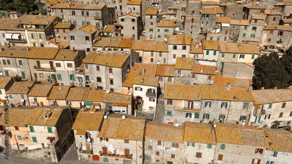 Aerial view of the sloping roofs of the houses in the historic center of Bracciano, in the metropolitan city of Rome, Italy. The orange color of traditional roofs predominates.