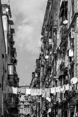 Fototapeta Naklejka Na Ścianę i Meble -  Facade in a narrow street in old town “Centro storico“ of historic italian metropole Naples. Balconys of typical residential building block of flats in rotten and weathered condition, black and white.