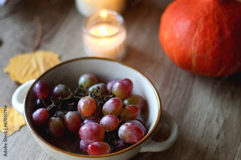 Cup of tea or coffee, plate with desserts, dried oranges, bowl of grapes, scented candles, vintage books, pumpkins and autumn leaves on the table. Autumnal hygge. Selective focus. Cup of tea or coffee, plate with desserts, dried oranges, bowl of grapes, scented candles, vintage books, pumpkins and autumn leaves on the table. Autumnal hygge. Selective focus.