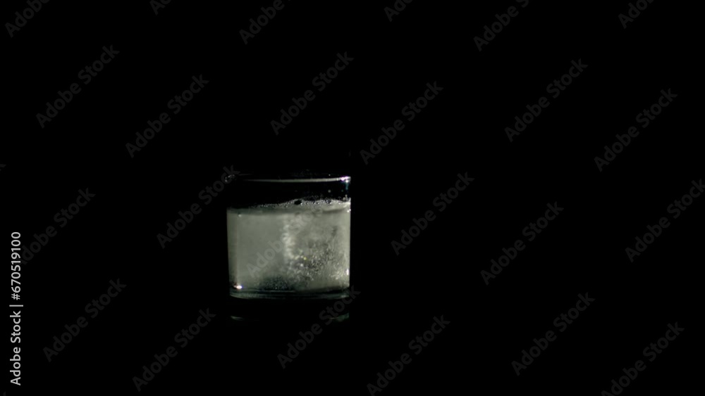 Effervescent tablet in the glass of water. Close-up of tablet bubbling in the glass of water on the black background. Slow motion, 4K Effervescent tablet in the glass of water. Close-up of tablet bubbling in the glass of water on the black background. Slow motion, 4K