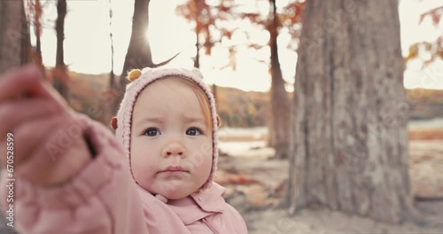 Child girl playing amid autumnal trees. Little girl in a autumnal park with cypress trees.