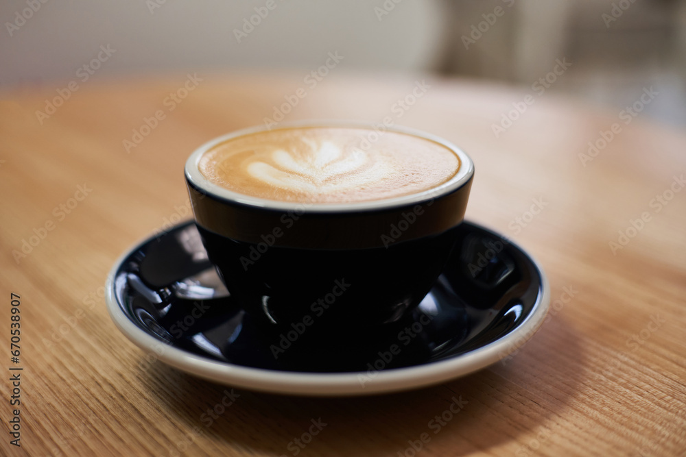 Fototapeta premium Cup of coffee on the table in cafe. Cappuccino or latte in mug. Enjoying time alone