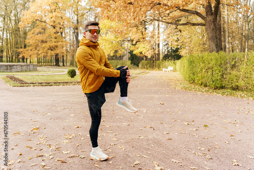 The athlete has an active and healthy lifestyle on weekends in the park. A confident and hardy man running alone. A running coach does a jogging exercise in athletic shoes. photo