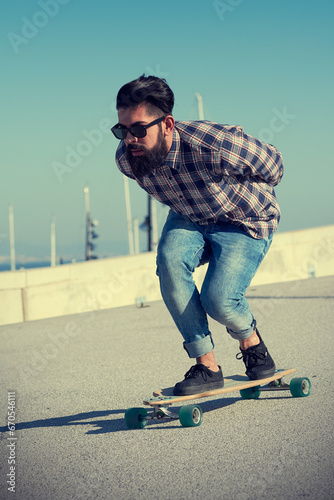 Man riding longboard with hands behind back