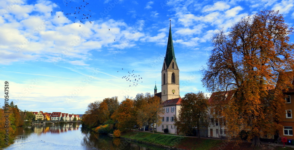 idyllischer Neckar in Rottenburg im Sonnenlicht im Herbst mit bunten Bäumen und Stiftskirche St. Moritz