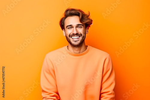Homme sympathique avec une barbe posant avec un pull orange sur un fond orange photo