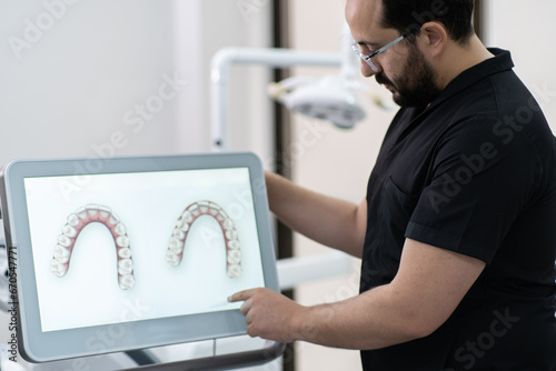 Skilled dentist showing lower and upper human jaws models on monitor presenting teeth treatment program at stomatology industry development conference