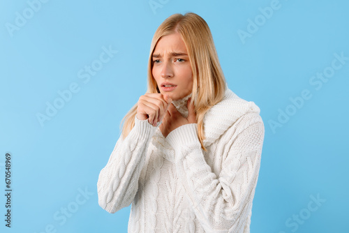Young lady with throat pain, coughing, blue background