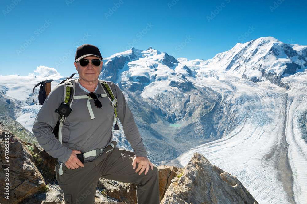 Switzerland travel -  Senior man hiking in the Swiss Alps with the Gorner glacier in the background