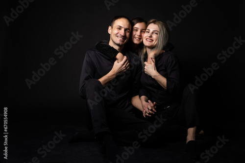 Happy young family with one child having fun together isolated on black.