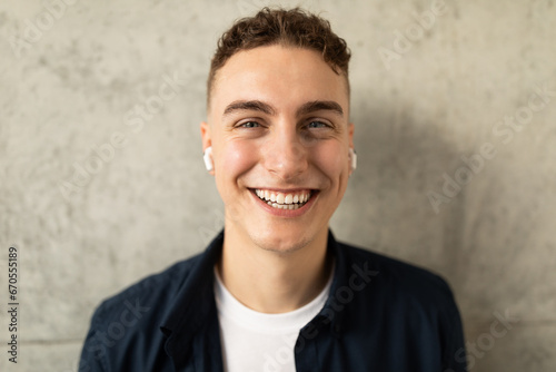 Smiling attractive young european guy in casual, wireless headphones enjoy lifestyle, listen music