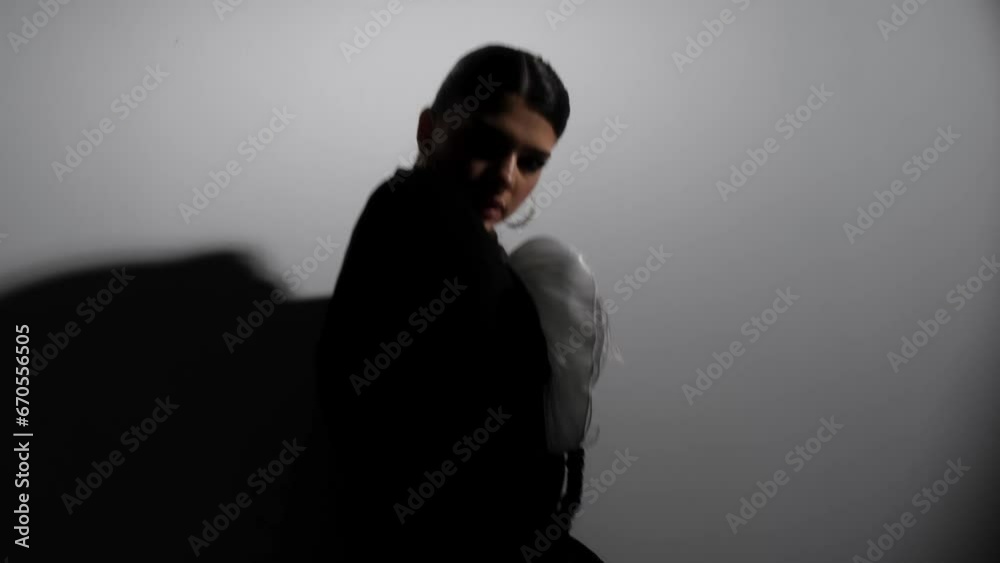 Beautiful confident brunette in a stylish suit. Fashionable model with bright makeup posing under flickering lights in the studio. The concept of advertising cosmetics and evening, vibrant lifestyle. Beautiful confident brunette in a stylish suit. Fashionable model with bright makeup posing under flickering lights in the studio. The concept of advertising cosmetics and evening, vibrant lifestyle.